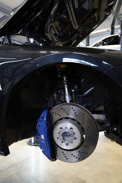 Eingebautes DCS+ Federbein vorne hinter blauem BMW M Bremssattel im Radhaus