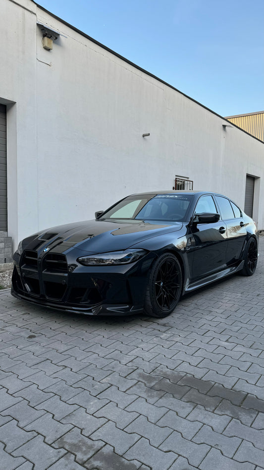 Schwarzer BMW M3 G80 mit glänzend schwarzen Frontschürzen-Lufteinlässen, Ansicht schräg vorne