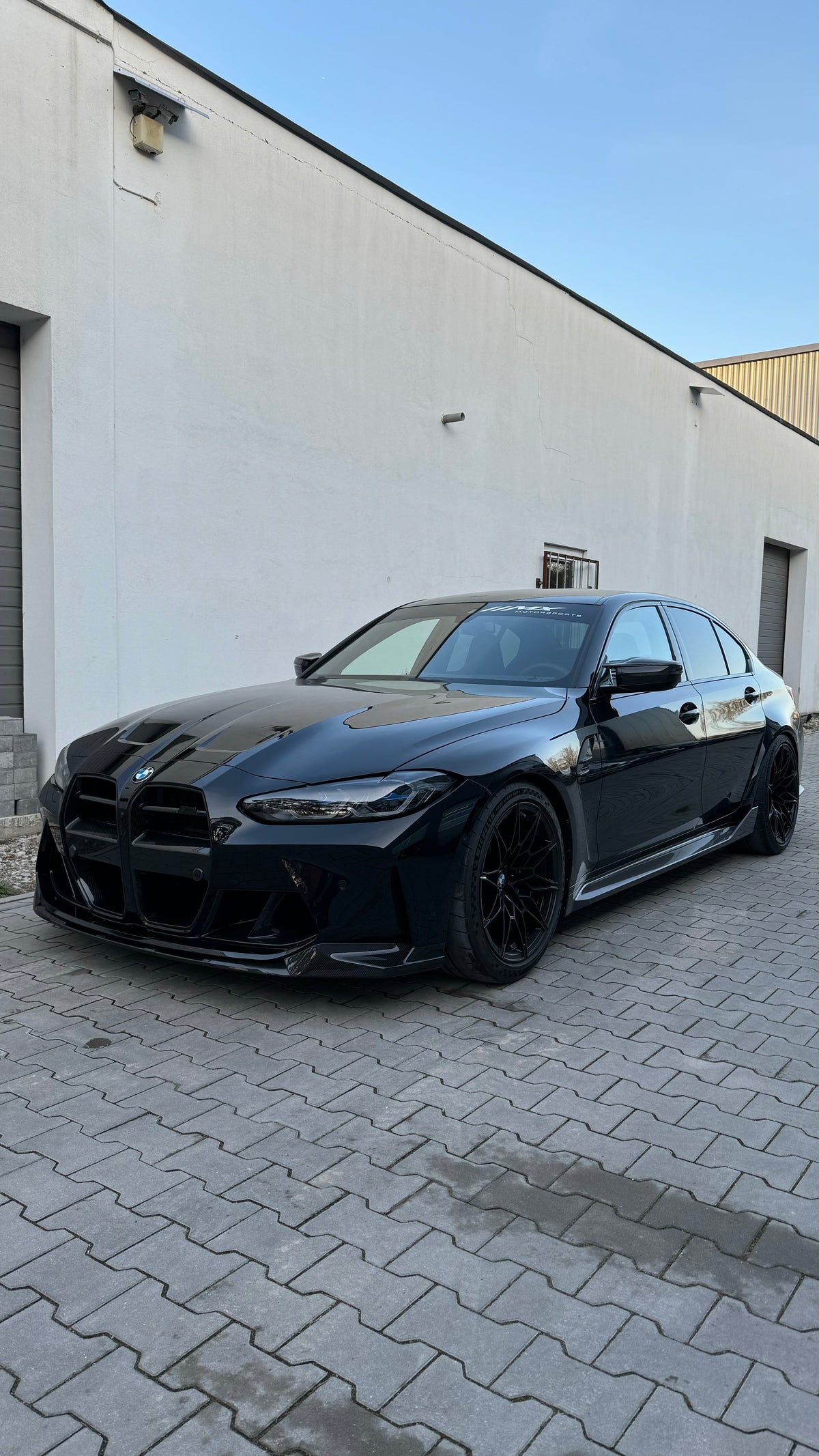 Schwarzer BMW M3 G80 mit glänzend schwarzen Frontschürzen-Lufteinlässen, Ansicht schräg vorne