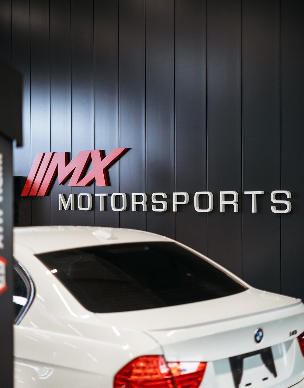 MX-Motorsports-Logo an der Wand der Werkstatt in Hirschaid, davor ein BMW M3